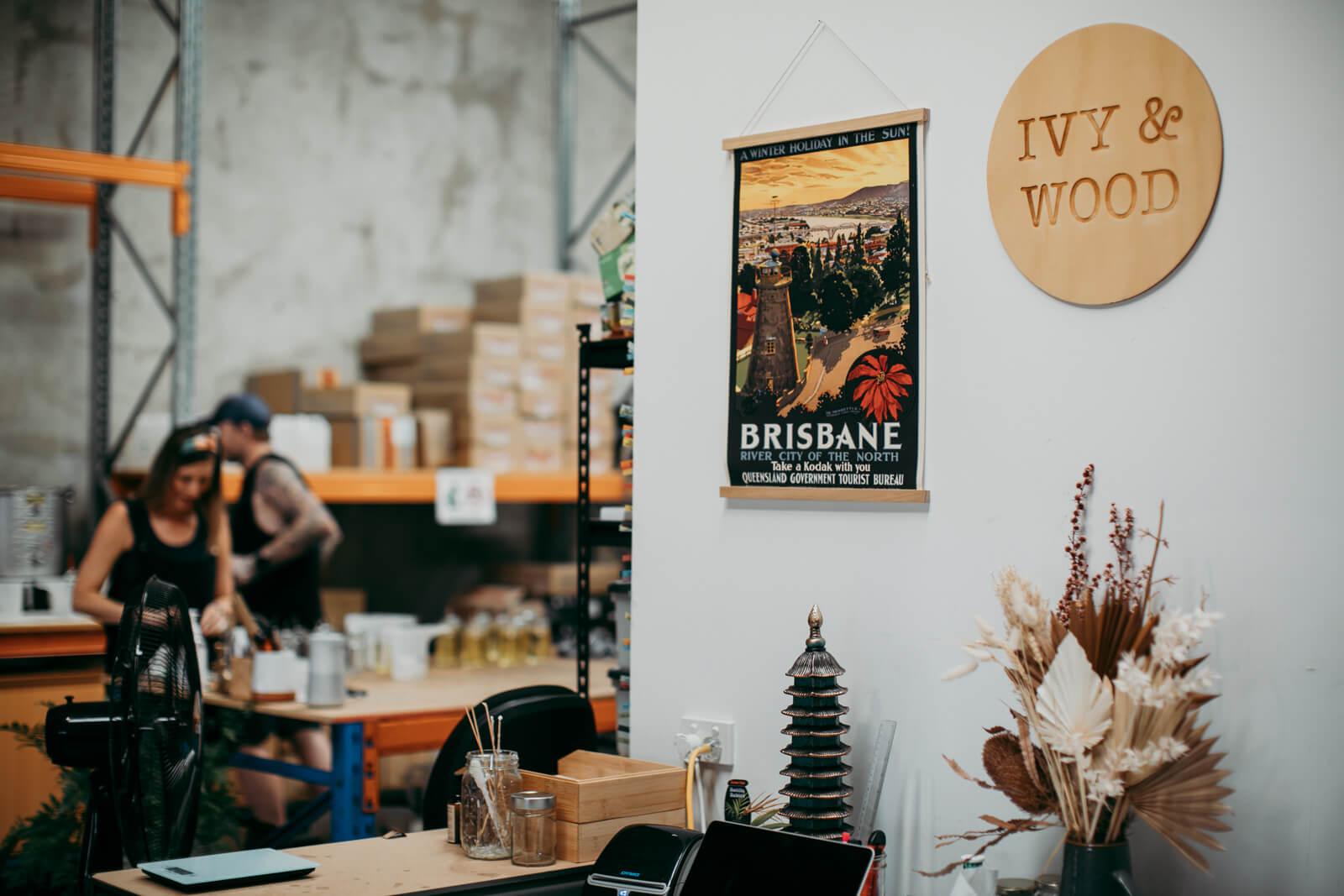 IVY & WOOD 位於布里斯本的工作室實景。牆上掛著城市海報與木質品牌標誌，呈現創辦人 Jess 與 Brad 專注於天然香氛創作的職人日常。