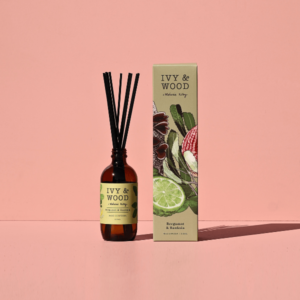 IVY&WOOD佛手柑與澳洲忍冬擴香瓶商品主圖，琥珀色玻璃瓶身搭配優雅黑色擴香竹與滿版植物插畫外盒，單純粉紅色背景與俐落採光陰影細節。