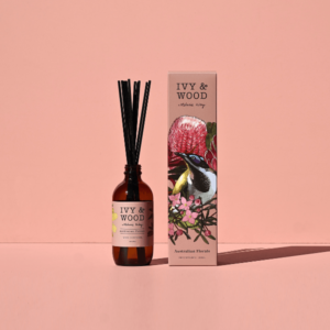 MUDITA 官網精選 IVY AND WOOD 澳洲花海秘境室內擴香瓶與 Melanie Kilby 聯名粉色插畫包裝外盒，置於乾淨輕奢粉膚色背景前，定錨洗鍊精品身份
